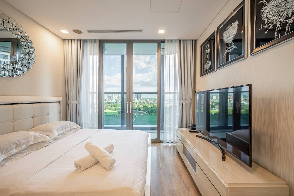Een moderne hotelkamer met een groot bed, een flatscreen-tv en een balkon met uitzicht over de stad.
