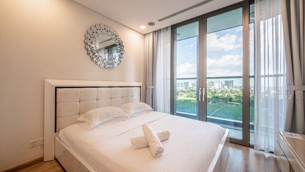 Habitación de hotel moderna con una cama grande, un espejo decorativo y vistas a la ciudad a través de la ventana.