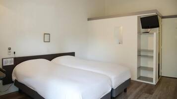 Une chambre d’hôtel avec un lit double, une table de chevet, un téléviseur fixé au mur et une armoire intégrée.