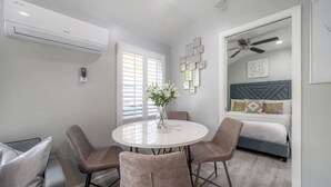 Una habitación moderna con una mesa de comedor redonda, cuatro sillas, una cama con cabecero y un equipo de aire acondicionado.