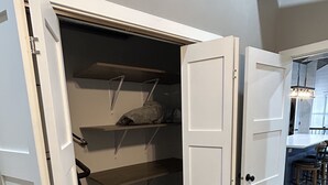 A walk-in closet with open doors, shelves, and a small cabinet. - Quaint, all new loft apt. located in a quiet country setting, minutes from town. (Fort Pierre)