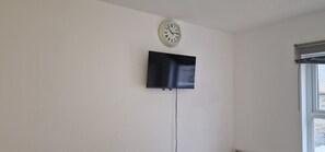 Enjoy a simple and functional space with a flat-screen TV, wall clock, and natural light.