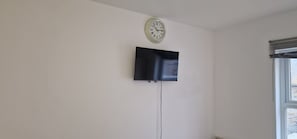 Enjoy a simple and functional space with a flat-screen TV, wall clock, and natural light.