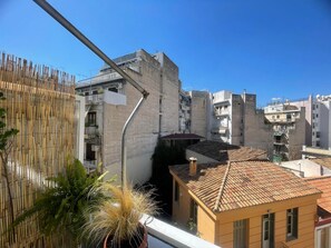 A residential area with a narrow street, buildings with balconies, and a bamboo fence. - Sunny Studio (Athens)