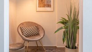 A chair with a checkered cushion, a potted plant, and a framed artwork on the wall.