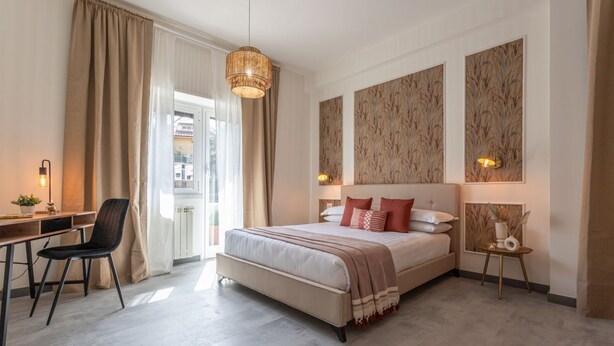 A modern bedroom with a large bed, a desk with a chair, and a small table with a lamp.