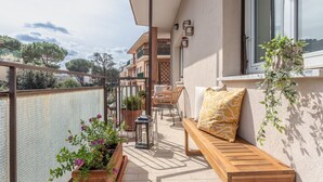 A balcony with a wooden bench, potted plants, and a lantern.