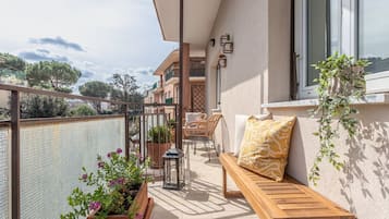Un balcone con una panca in legno, piante in vaso e una lanterna.