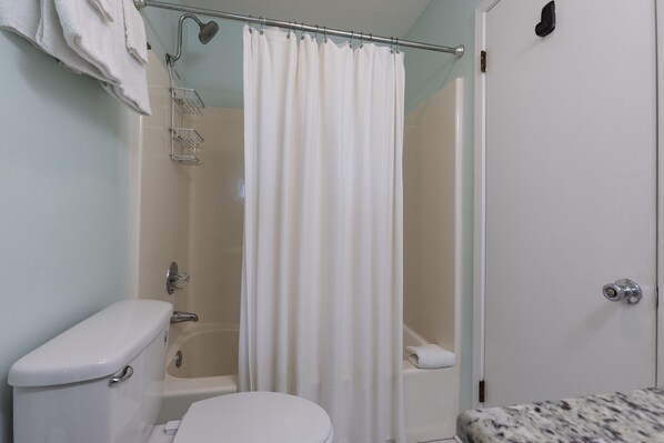 A bathroom with a toilet, bathtub, and shower curtain.
