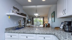 A modern kitchen with granite countertops, white cabinetry, and a coffee maker. - Pal306- Super Cute! Awesome Pool, & Beach Gear Included! Location X3! (Orange Beach)