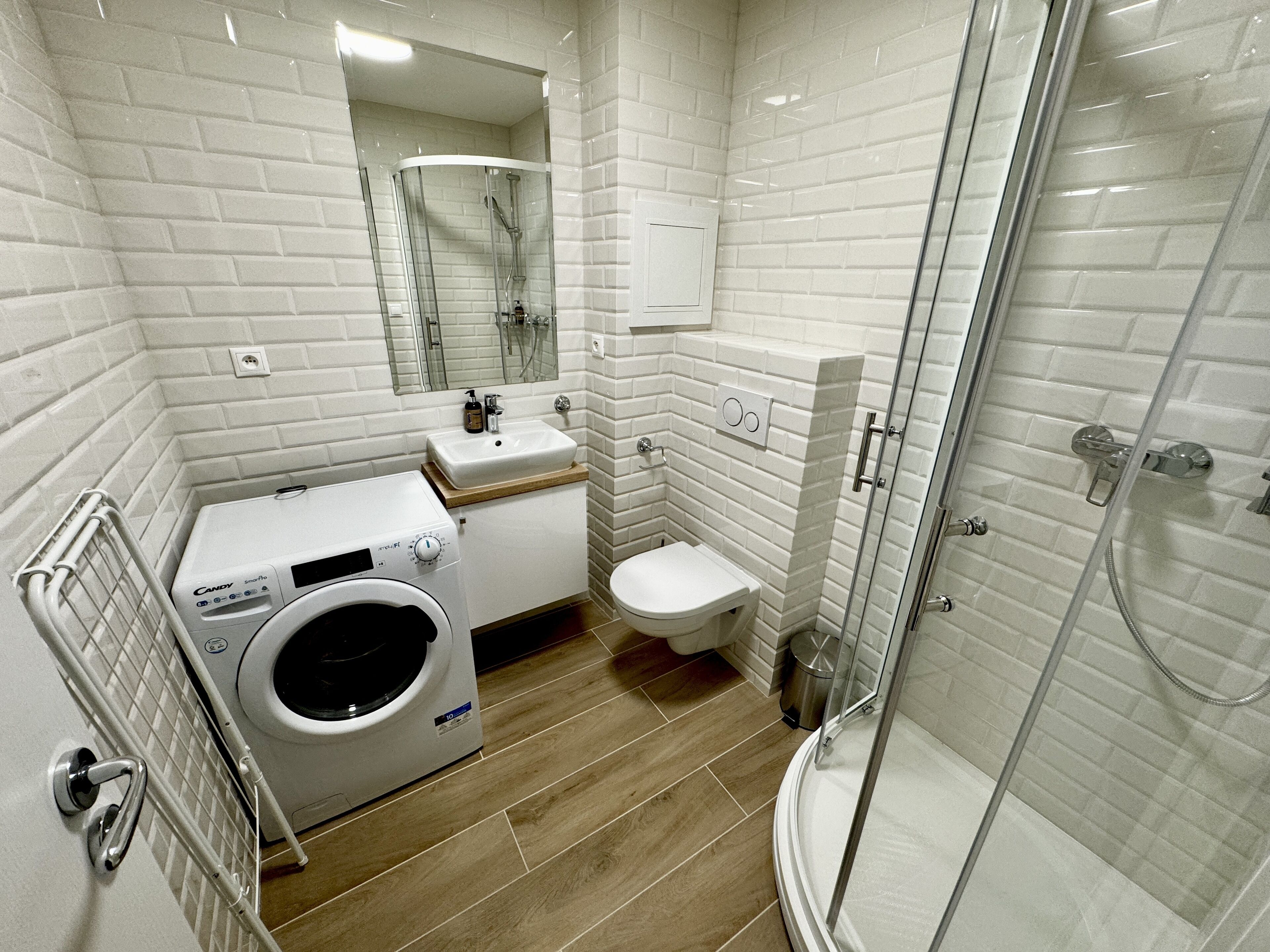 Ein modernes Badezimmer mit integrierter Waschmaschine, Toilette und einer Duschkabine.