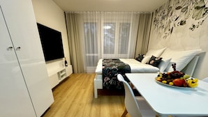 Une chambre d’hôtel moderne équipée d’un lit, d’une table à manger avec des fruits, d’une télévision et d’une armoire.