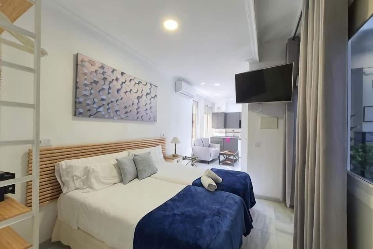 A bedroom with a bed, a TV, and a view of the outside.
