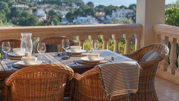 A table set for two with wicker chairs, a view of the sea, and a balcony railing. - Villa Bendinat 10: A luxurious oasis in Puerto Portals, Calvia (Calvi à)