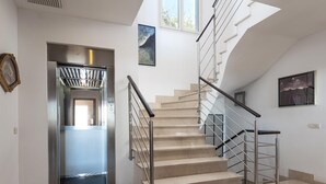 A modern staircase with metal railings and beige steps, leading to an elevator. - Villa Bendinat 10: A luxurious oasis in Puerto Portals, Calvia (Calvià)