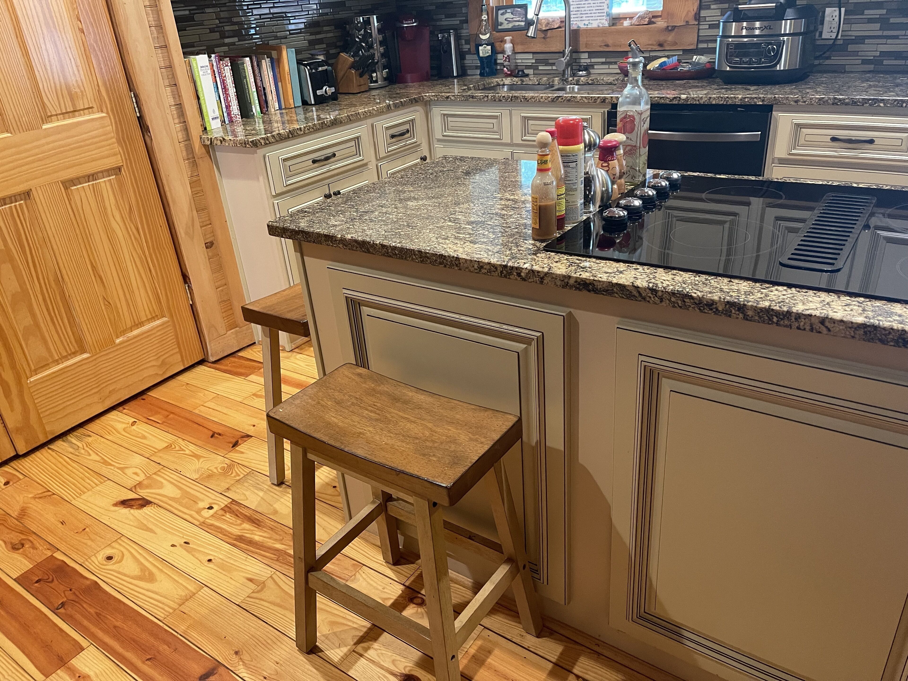 A kitchen with a granite countertop, wooden stools, and a built-in oven.