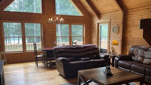 L’intérieur chaleureux d’un chalet avec un plancher en bois, un canapé, une table basse et un coin repas.