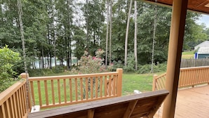 Une terrasse en bois avec une balançoire et une vue sur un lac et des arbres.