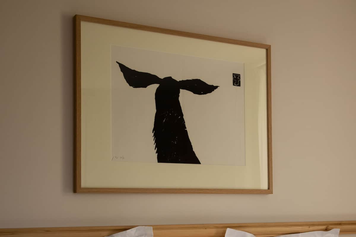 Une chambre d’hôtel avec un lit recouvert de linge de lit blanc et une œuvre d’art encadrée au-dessus.