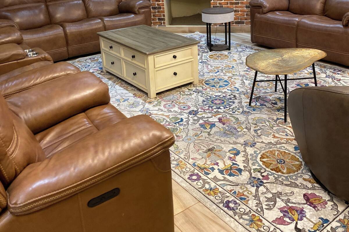 A living room with leather sofas, a flat-screen TV, a brick fireplace, and a decorative rug.