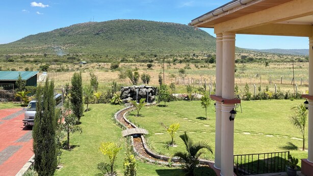 A landscaped garden with a stone pathway, a mountain in the background, and a building with a covered porch. - Mara Meguarra Sanctuary (Maasai Mara)