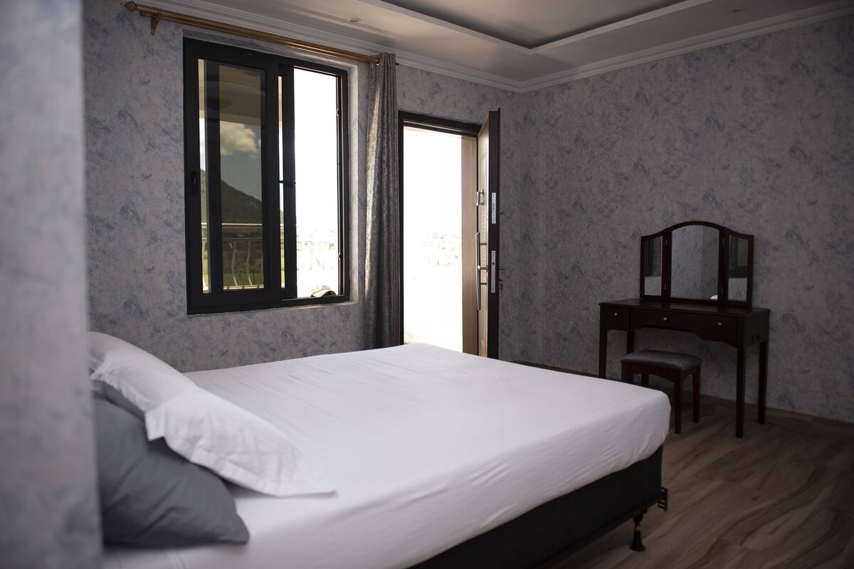 A bedroom with a bed, a desk, and a window.