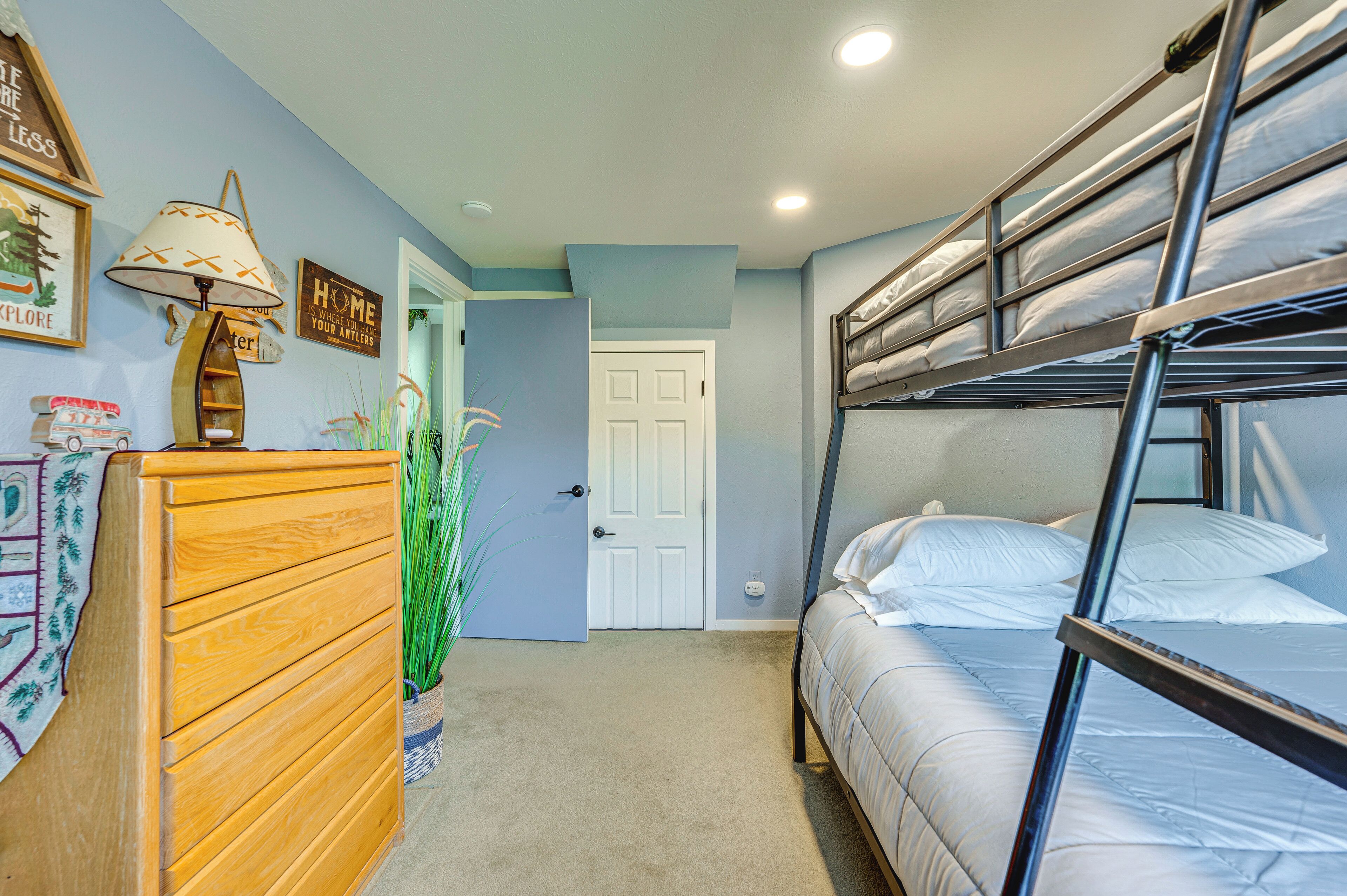 A bunk bed room with a wooden dresser, a lamp, and wall decorations.