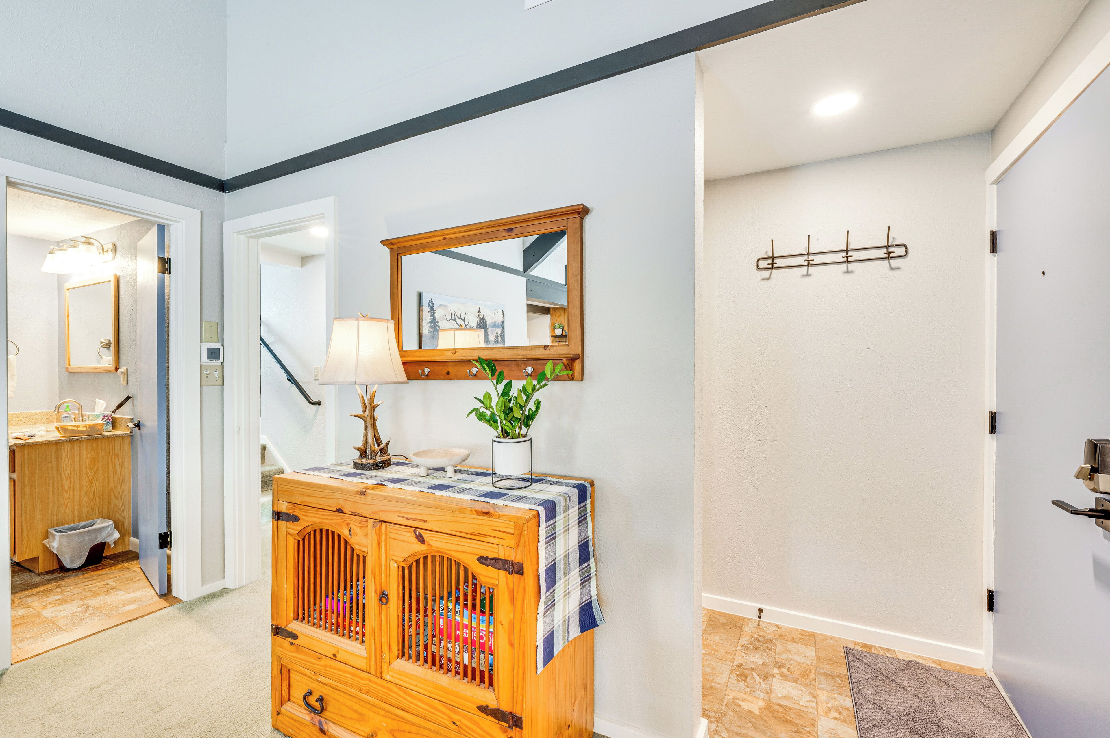 A hallway with a wooden cabinet, a mirror, and a coat rack.