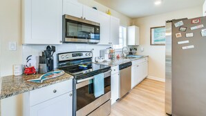 A modern kitchen with white cabinets, stainless steel appliances, and a granite countertop. - 4 Mi to Beach: Charming Port Charlotte Home! (Port Charlotte)