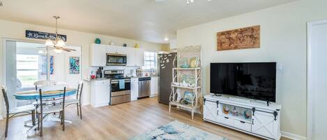 A spacious living area with a dining table, kitchen, and a TV.