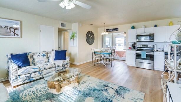 A living room with a sofa, coffee table, and a dining area with chairs and a table. There is a kitchen with an oven and microwave. - 4 Mi to Beach: Charming Port Charlotte Home! (Port Charlotte)