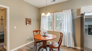 A dining area with a wooden table and chairs, a chandelier, and a refrigerator. - Bright Kingston Springs Home < 22 Mi to Nashville (Kingston Springs)