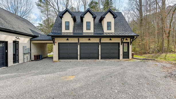 A building with a symmetrical facade, three garage doors, and a gravel driveway. - Bright Kingston Springs Home < 22 Mi to Nashville (Kingston Springs)