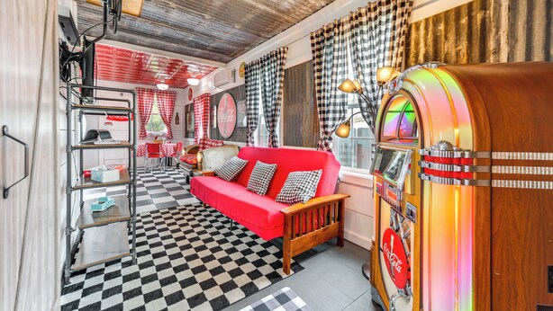 A retro-themed room with a red sofa, checkered floor, jukebox, and vintage decor. - Fifties Diner-style Llano Home w/ Shared Fire Pit (Llano)