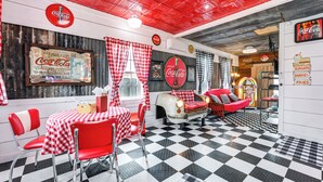 A retro-themed restaurant with checkered flooring, red and white decor, and vintage Coca-Cola memorabilia. - Fifties Diner-style Llano Home w/ Shared Fire Pit (Llano)