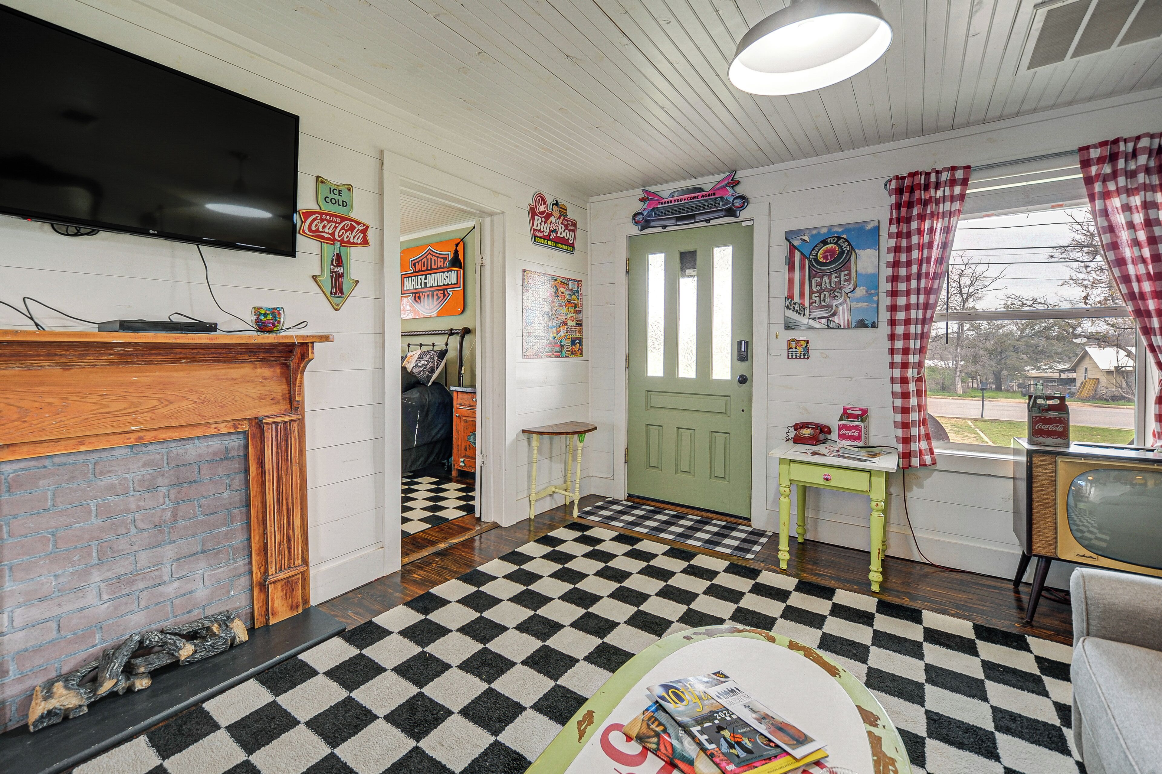 A living room with a checkered floor, a fireplace, a television, and various wall decorations.