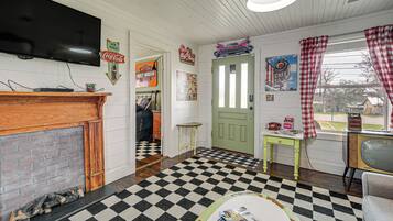 A living room with a checkered floor, a fireplace, a television, and various wall decorations.