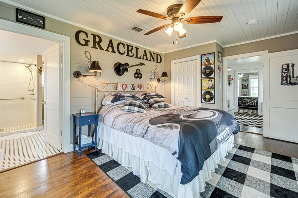 A bedroom with a large bed, a ceiling fan, and a wall with 'GRACELAND' written on it. - Retro Retreat in Llano w/ Screened Porch! (Llano)