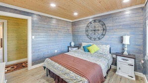 A bedroom with a bed, nightstands, a wall clock, and a decorative wall piece. - 4 Mi to Whitney Lake: Home on 30 Acres! (Whitney)