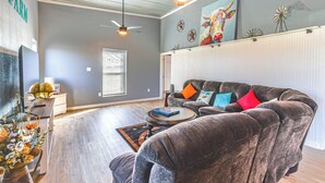 A living room with a dark brown sofa, a coffee table, and a ceiling fan. - 4 Mi to Whitney Lake: Home on 30 Acres! (Whitney)