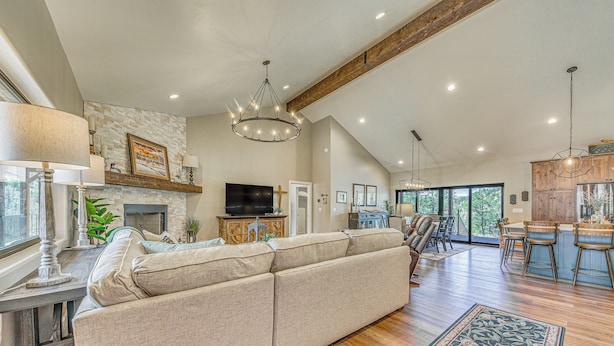 A spacious living room with a large beige sectional sofa, a fireplace, and a dining area with wooden cabinets and a bar. - Spacious Ruidoso Home: Hike, Golf, Ski & More! (Ruidoso)