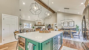 A spacious kitchen with a central island, pendant lighting, and a dining area with a wooden table and chairs. - Spacious Ruidoso Home: Hike, Golf, Ski & More! (Ruidoso)