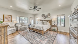 A bedroom with a large bed, two armchairs, a wooden dresser, and a ceiling fan. - Spacious Ruidoso Home: Hike, Golf, Ski & More! (Ruidoso)
