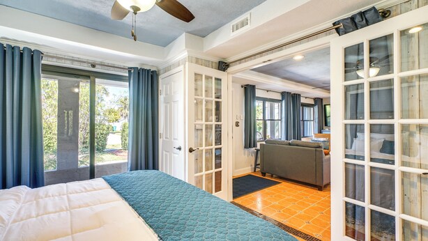 A bedroom with a bed, a ceiling fan, and a view of the outside. - Port Charlotte Vacation Rental w/ Heated Pool! (Port Charlotte)