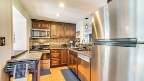A modern kitchen with stainless steel appliances, wooden cabinets, and a tiled backsplash. - Port Charlotte Vacation Rental w/ Heated Pool! (Port Charlotte)