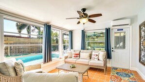 A sunlit room with a pool view, wicker furniture, and a ceiling fan. - Port Charlotte Vacation Rental w/ Heated Pool! (Port Charlotte)