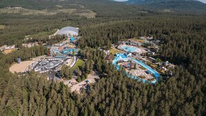 An aerial view of a resort with multiple swimming pools, a large building, and surrounding forested hills. - Grend Bø (Midt-Telemark)