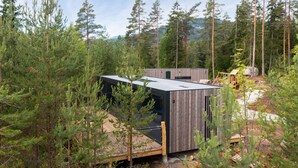 A modern cabin with a wooden exterior, surrounded by dense forest. - Grend Bø (Midt-Telemark)