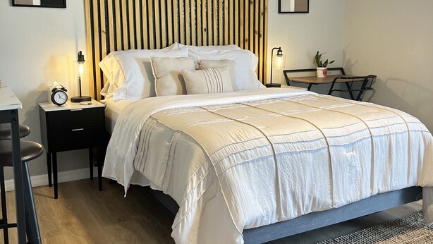 A neatly arranged bedroom with a bed, bedside tables, a desk, and a chair. - The perfect blend of comfort and convenience in our cozy studio apartment (CAPE CORAL FL)
