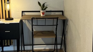 A corner room with a wooden desk, a small potted plant, and a framed abstract artwork on the wall. - The perfect blend of comfort and convenience in our cozy studio apartment (CAPE CORAL FL)